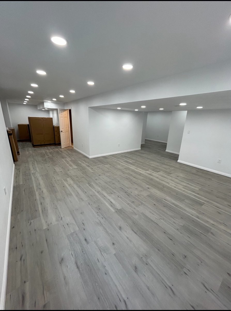 Finished basement with gray luxury vinyl plank flooring, fresh drywall and recessed lighting