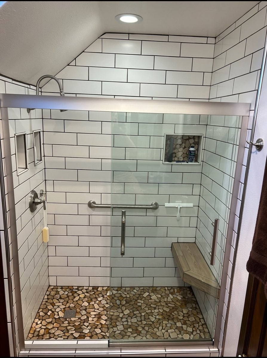 Walk-in shower with white subway tile, a river-rock pebble floor and a built-in bench