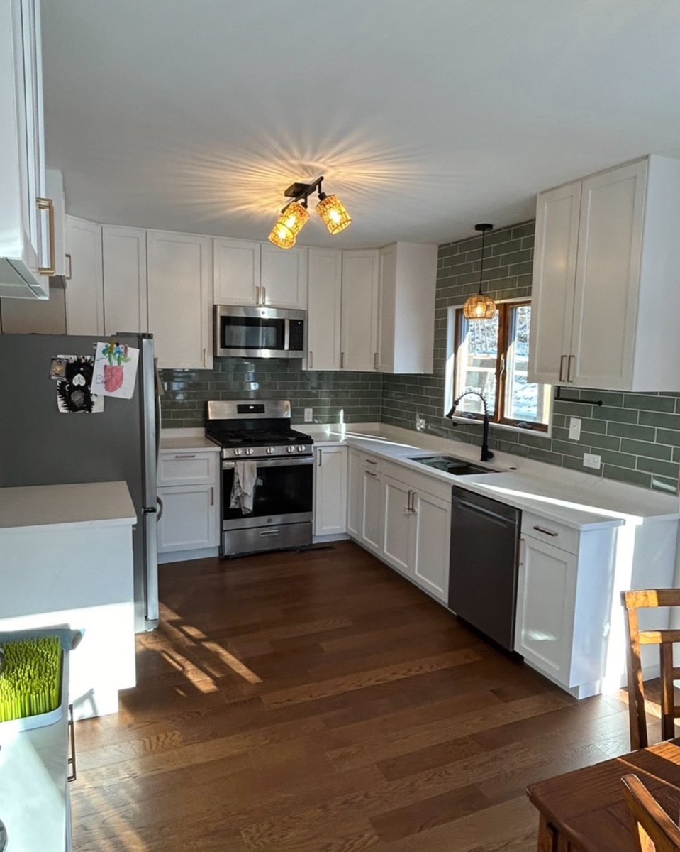 Kitchen remodel with white shaker cabinets, green subway tile backsplash and refinished hardwood floors